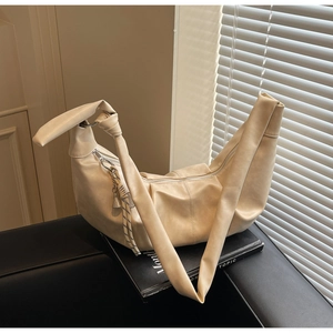 Detail view of beige crescent bag featuring soft faux leather and knotted strap design