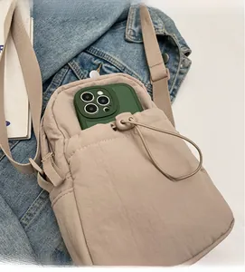 Detail of durable drawstring front pocket on a light khaki nylon crossbody phone bag