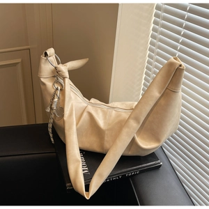 Detail of cream shoulder bag with knotted strap, silver ring and tennis racket charm
