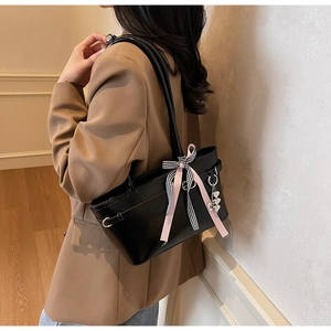 Détail du sac cabas en cuir noir avec ruban rose et breloque en forme de cœur argenté