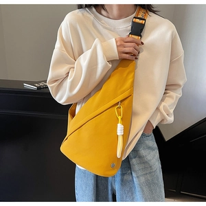 Detail of a bright yellow nylon chest bag featuring a letter printed strap and rope zipper pull