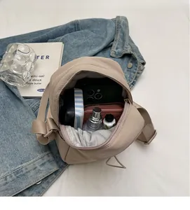 Internal capacity of beige nylon quilted crossbody bag showing smartphone and essentials