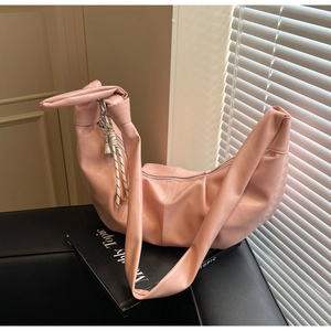 Detail of pink half-moon bag featuring soft leather texture and knotted shoulder strap