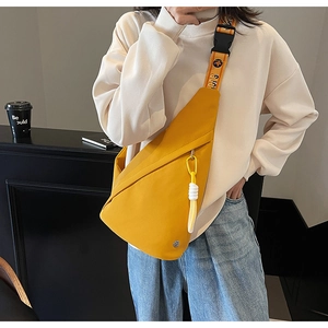 Close-up of bright yellow nylon sling bag with letter jacquard strap and rope detail