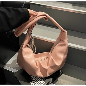 Close-up of pink ruched dumpling bag with wide shoulder strap on grey steps