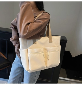 Close-up of minimalist off-white canvas tote bag showing multiple functional front pockets