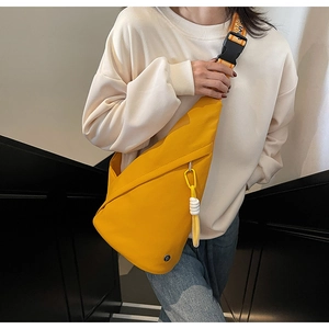 Detail of yellow crossbody sling bag featuring wide lettered strap and utility buckle