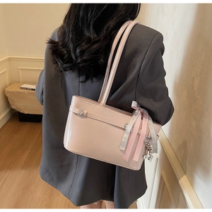 Détail d'un sac à bandoulière rose brillant avec nœud et breloque cœur sur mannequin