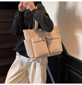 Detailed view of beige nylon tote bag featuring front dual zipper pockets and large capacity