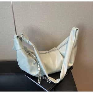 Detail of light green crescent hobo bag with knotted strap and soft pleated PU leather