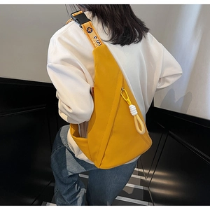 Side view of a bright yellow sling bag with a blue logo strap and decorative knot detail