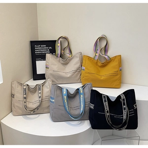 Détail de cabas multicolores avec de larges bretelles imprimées et des poignées à rivets