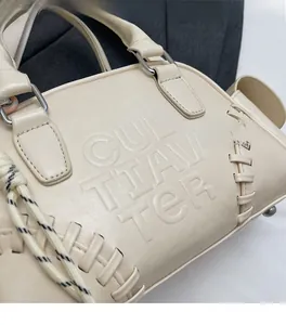 Detail of cream shoulder bag with woven rope accents and embossed lettering texture