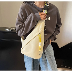Close-up of cream crossbody bag with geometric design and patterned strap on a model