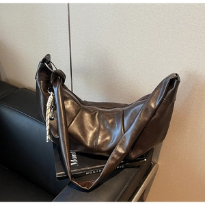 Detail view of the deep brown pleated moon bag featuring a woven rope charm and zipper