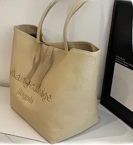 Detail of minimalist beige canvas tote bag featuring premium texture and 3D embroidery