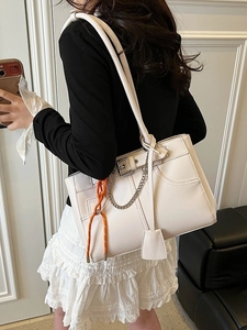 Off-white large capacity tote bag with metal chain and orange accent on a female model