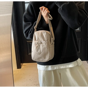 Detail of minimalist nylon crossbody bag featuring drawstring pocket and wrinkled texture