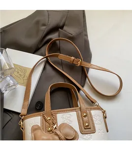 Detail der cremefarbenen Beuteltasche mit Sternprägung, braunem Rand und Bärenanhänger