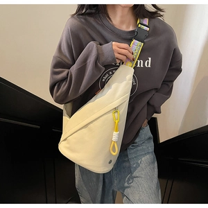 Detail of off-white crossbody bag with vibrant yellow lettered strap and plastic buckle