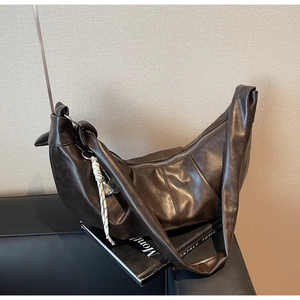 Detail of dark brown croissant bag with soft leather texture and woven knot accent