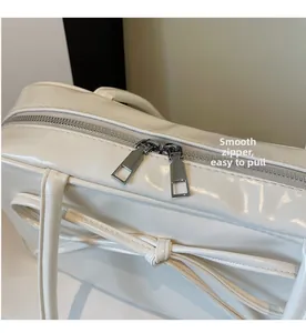 Close-up of smooth metal dual zippers and leather bow on cream shoulder bag
