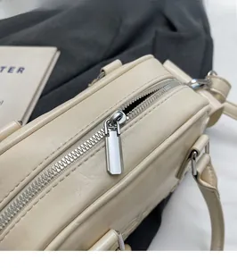 Detail shot of the smooth silver metal zipper on a cream leather shoulder bag