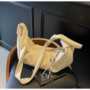 Detail of creamy white faux leather hobo bag with knotted strap and braided tassel charm