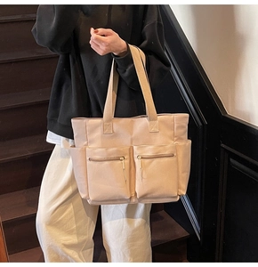 Beige canvas tote bag with front zipper pockets shown on vintage wooden stairs