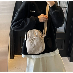 Detail of light beige nylon crossbody bag featuring a stylish drawstring outer pocket