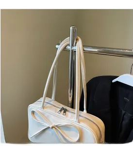 Detailed view of white tote bag with bow detail hanging on a metallic hanger