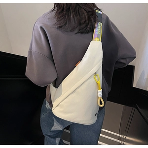 Detail of off-white crossbody bag featuring a colorful jacquard strap and triangle shape