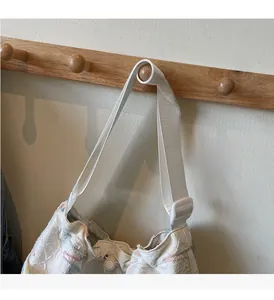 Detail of white quilted canvas tote with colorful stitching and adjustable nylon strap