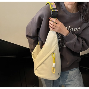 Detail of off-white canvas crossbody bag with yellow zipper and geometric jacquard strap