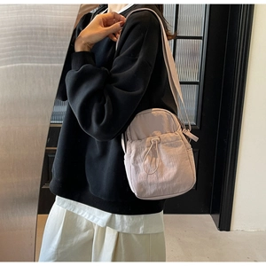 Detail of light purple nylon crossbody bag featuring drawstring pocket and slim strap