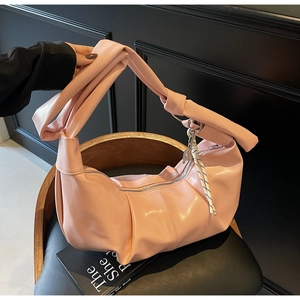 Detailed view of pink pleated crescent bag with knotted strap and striped pendant detail