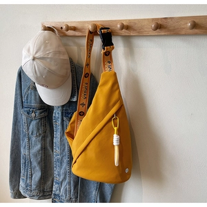 Detail of trendy yellow crossbody bag with printed shoulder strap and decorative knot