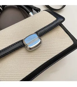 Détail d'un sac bandoulière bicolore en tissu beige avec fermoir en métal argenté