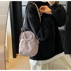Detail of light purple nylon crossbody bag featuring drawstring pocket and wrinkled texture
