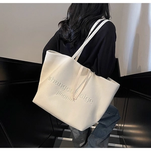 Close-up of stylish off-white canvas tote bag with textured embossed lettering detail