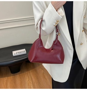 Detail of wine red hobo shoulder bag in shiny leather texture worn with a white blazer