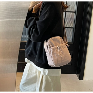 Detailed side view of a lilac drawstring crossbody bag worn by a model in modern interior