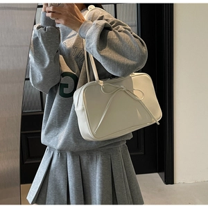 Close-up of white leather tote bag with a 3D ribbon bow and long shoulder straps