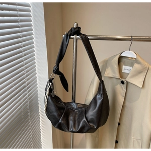 Detail shot of black hobo bag showing pleated crescent design and knotted shoulder strap