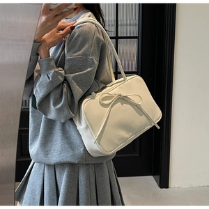 Mirror selfie showing a beige tote bag with a bow detail and matte leather finish