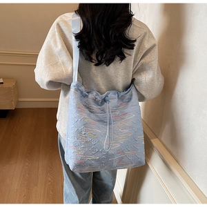 Detail of light blue quilted tote bag with wave embroidery and drawstring closure