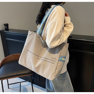 Détail du sac cabas en toile avec bandoulière géométrique large et texte imprimé design