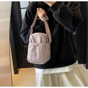 Detailed shot of a lightweight lavender nylon crossbody bag with drawstring pocket design