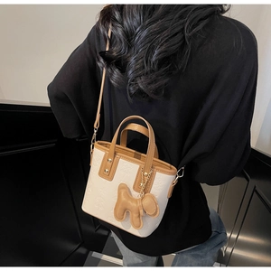 Detail einer beige-braunen Mini-Tote-Bag mit Sternprägung und süßem Hundeanhänger