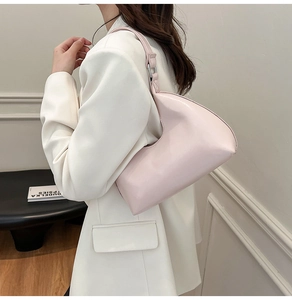 Side view of a light pink minimalist underarm bag with glossy faux leather and silver rings